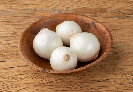 White onions in a bowl over wooden table.の写真素材
