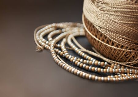 Golden threads and beads on dark backgroundの写真素材