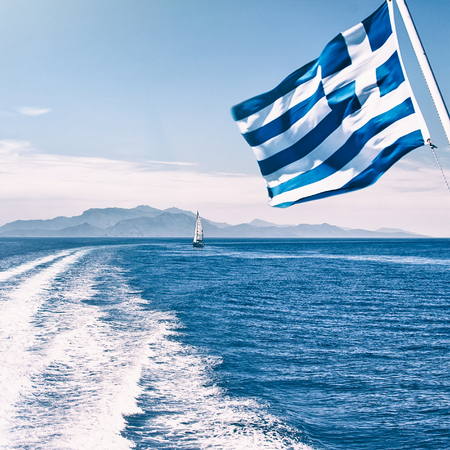 Speed boat traces on water in the Aegean sea little boat and flag of Greece in motion. Europeの写真素材