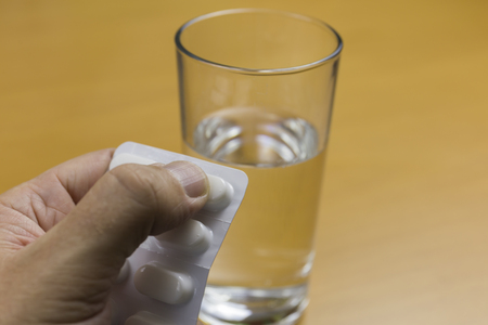 Hand with tablets and a glass of waterの写真素材