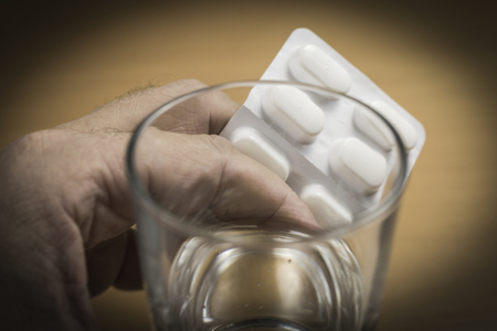 Hand with tablets and a glass of waterの写真素材