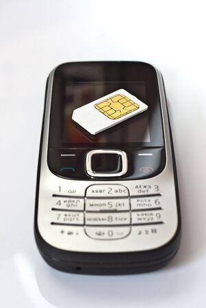 Mobile telephone with black and silver body lies on a white surfaceの写真素材