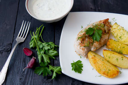 grilled chicken breast with roasted potatoes on white plateの写真素材