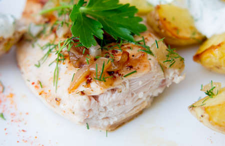 grilled chicken breast with roasted potatoes on white plateの写真素材