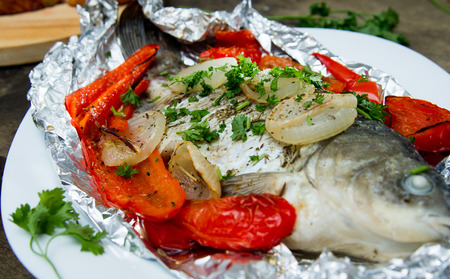 fish baked in foil with peppers, onions and herbsの写真素材
