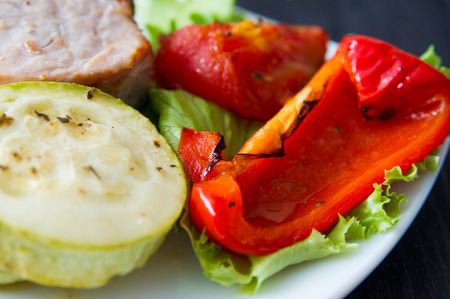 roasted pork steak with grilled vegetables on white plateの写真素材