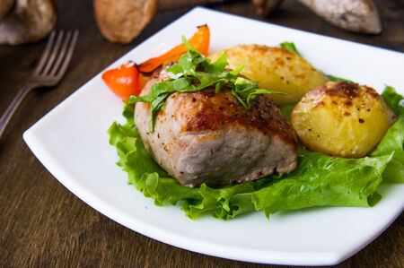 Pork steak with baked potato and mushroom sauce on white plateの写真素材