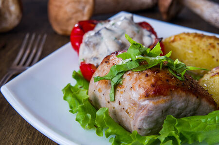 Pork steak with baked potato and mushroom sauce on white plateの写真素材