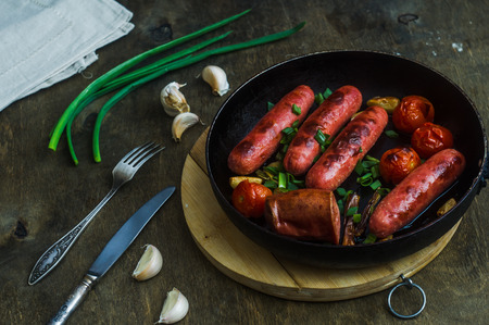 grilled sausages with vegetables and herbs in a frying panの写真素材
