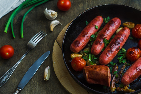 grilled sausages with vegetables and herbs in a frying panの写真素材