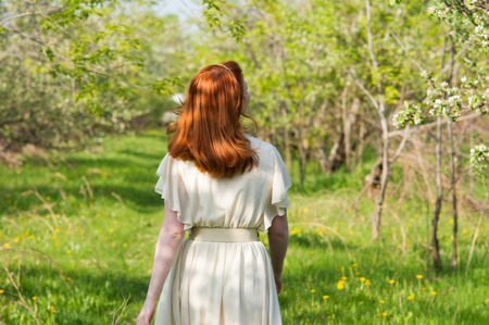 lovely red-haired girl walks in apple orchardの写真素材