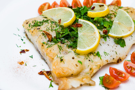 grilled fish with vegetables and cream sauce on white plate