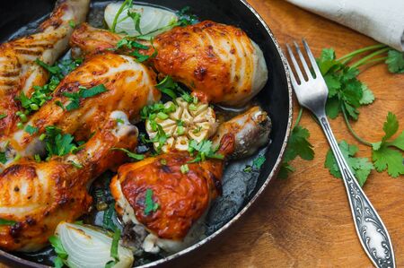 fried chicken drumsticks in a frying pan on wooden tableの写真素材