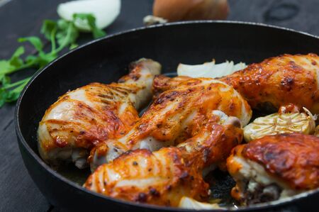 fried chicken drumsticks in a frying pan on wooden table