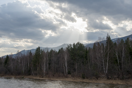 The spring river flows at the foot of the mountain ridgeの写真素材