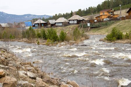 A rough mountain river flows next to the villageの写真素材