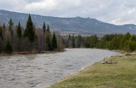 The spring river flows at the foot of the mountain ridgeの写真素材