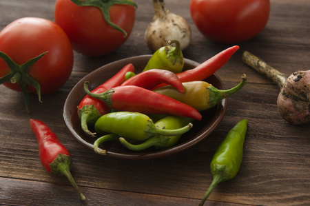 Ripe red tomatoes, hot chili peppers, garlic on a wooden tableの写真素材