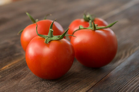 Juicy ripe red tomatoes on a wooden tableの写真素材