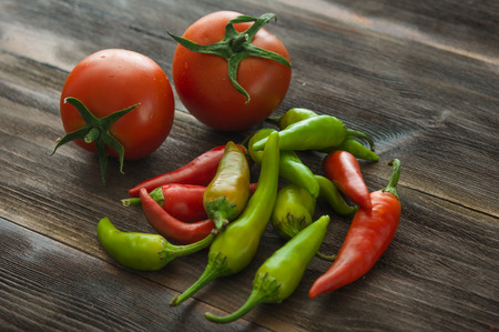 Ripe red tomatoes, hot chili pepper on a wooden tableの写真素材