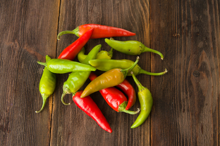 Small colorful chili peppers on a wooden tableの写真素材