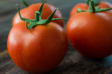 Juicy ripe red tomatoes on a wooden tableの写真素材