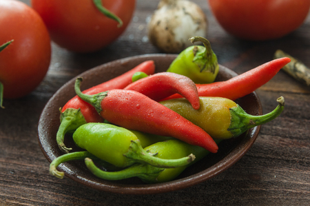Ripe red tomatoes, hot chili peppers, garlic on a wooden tableの写真素材