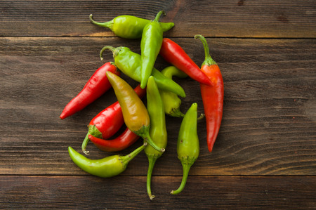 Small colorful chili peppers on a wooden tableの写真素材