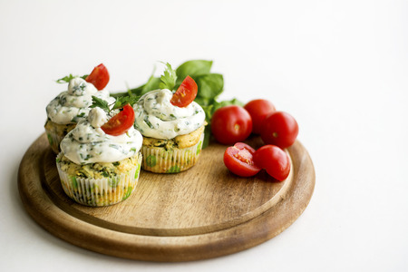Spinach cupcakes with cheese cream frosting, green fresh onion on a wooden board with cherry tomatoes and spinach leavesの写真素材