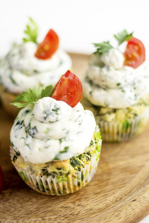 Spinach cupcakes with cheese cream frosting, green fresh onion on a wooden boardの写真素材