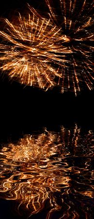Explosive fireworks shooting into the black sky and reflectionsの写真素材