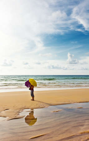 Girl with umbrellas at the tropical beach の写真素材