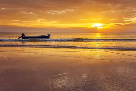 Boat on the beach at sunset in tide time の写真素材
