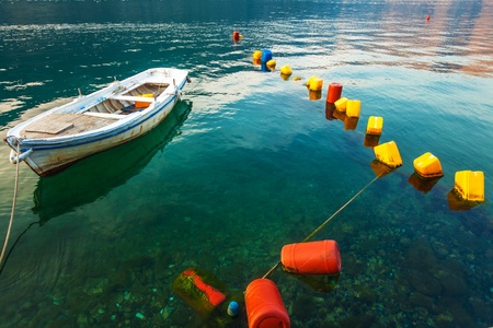Small boat in sea with row of buoys  Montenegroの写真素材