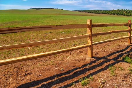 An old wood fence with a green country field behind itの写真素材