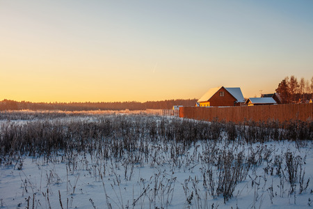 Winter sunset in field near the villageの写真素材