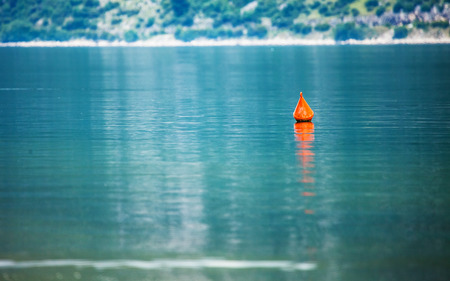 Single red buoy on a calm sea surface