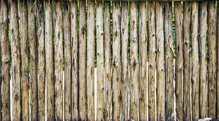 Old grunge fence of wood trunks, background textureの写真素材