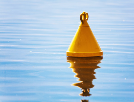 Single yellow buoy on a calm sea surfaceの写真素材