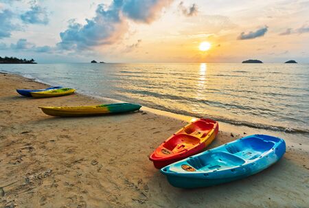 Kayaks on the beach during sunsetの写真素材