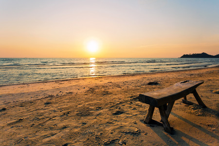 wooden bench on the sandy beach with views on sunsetの写真素材