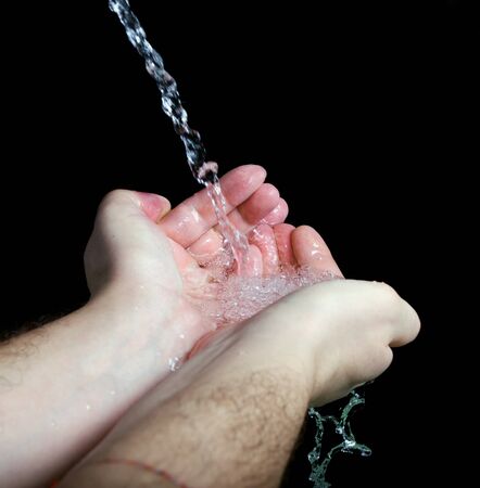 Hands in splashing water on blackの写真素材
