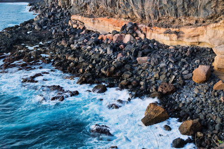 Top view of the sea and the waves crashing on the shore rocks in the sunlight. Tenerife, Canary Islands, Spainの写真素材