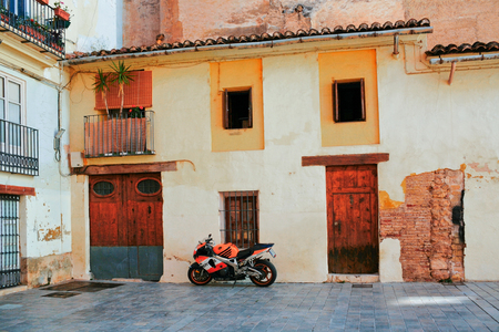 VALENCIA, SPAIN - APRIL 24, 2016: In the old city of Valencia, a motorcycle is parked between two entrances to the house in the traditional Mediterranean styleのeditorial素材