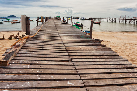 Boats near the pier in tropical sea under gloomy dramatic sky. Thailandの写真素材