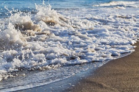 Ocean wave with foam coming to the black sand beach