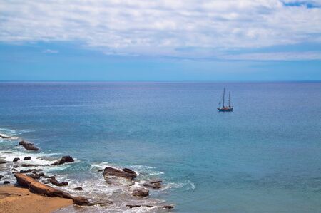 Atlantic Ocean with a sailing boat in the scene from La Tejita beach, Tenerife, Canary Islands,...