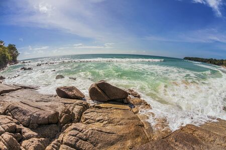 fisheye view on stones beach with blue sky and sunの写真素材