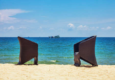 Sun chairs at beach against blue sea at sun dayの写真素材
