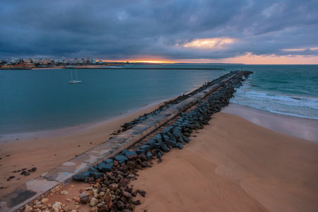 Pier to famous old farol de Portimao molhe este under gloomy sunset.Portugalの写真素材